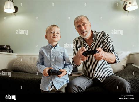 Grandfather And Grandson Playing Video Games On Computer With Joystick