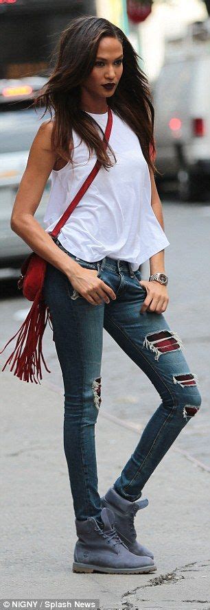 A Woman In Ripped Jeans Is Standing On The Street