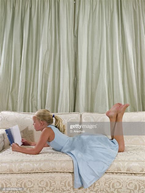 Girl Lying On Sofa Reading Book In Living Room Side View Photo Getty