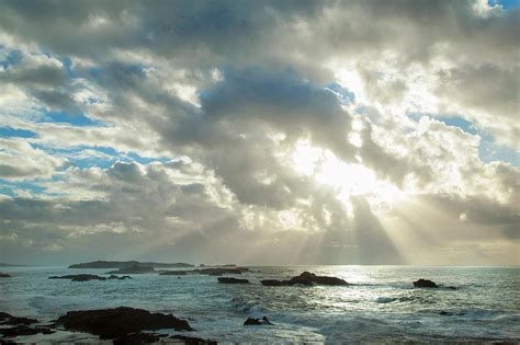 Sun Shining Through Clouds Over Beach By Henglein And Steets