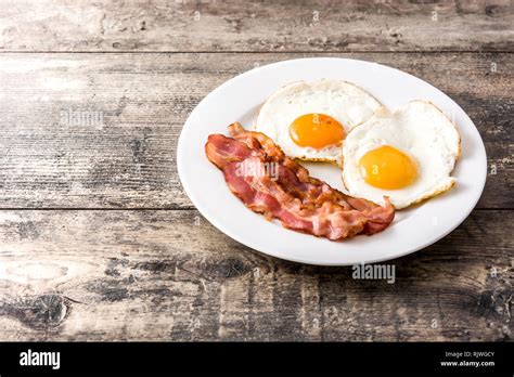 Fried Eggs And Bacon For Breakfast On Wooden Table Copyspace Stock