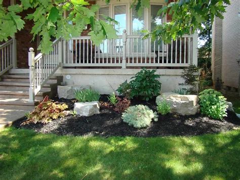 Evergreen landscape ideas in todays front of house. Beautiful small garden with Armour stone, shrubs, and ...