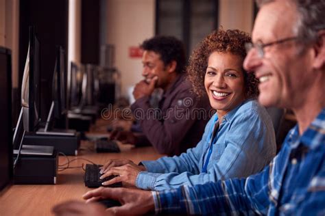 Group Of Mature Adult Students In Class Working At Computers In College