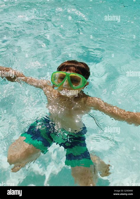 A Young Boy In A Snorkeling Mask Underwater In An Outdoor Swimming Pool