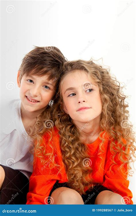 Curly Haired Girl In An Orange Long Sleeve T Shirt Sits Next To Her