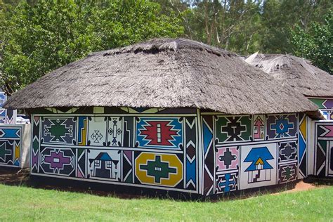 A Thatched Hut With Colorful Designs On The Side And Grass Roof