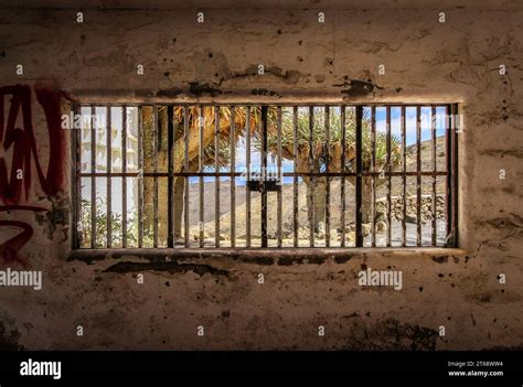 An aged jail with graffiti covering the walls and barred windows Stock