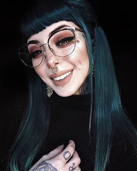 a woman with green hair wearing glasses and piercings