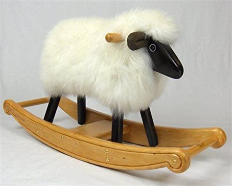 A Toy Sheep Sitting On Top Of A Wooden Sleigh With White Fur And Black Feet