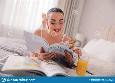 mujer feliz leyendo revista en la cama foto de archivo imagen de mentira noticias 222169988