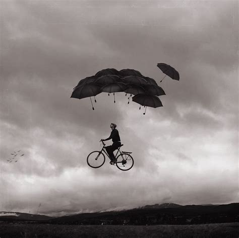 A Man Riding A Bike While Flying Through The Air With Umbrellas Over
