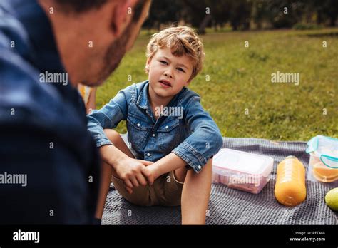 Cute Little Boy Hablando Con Su Padre Mientras Están Sentados En Manta
