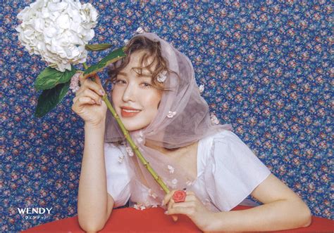 A Woman Holding A Flower In Front Of Her Face And Wearing A Veil Over