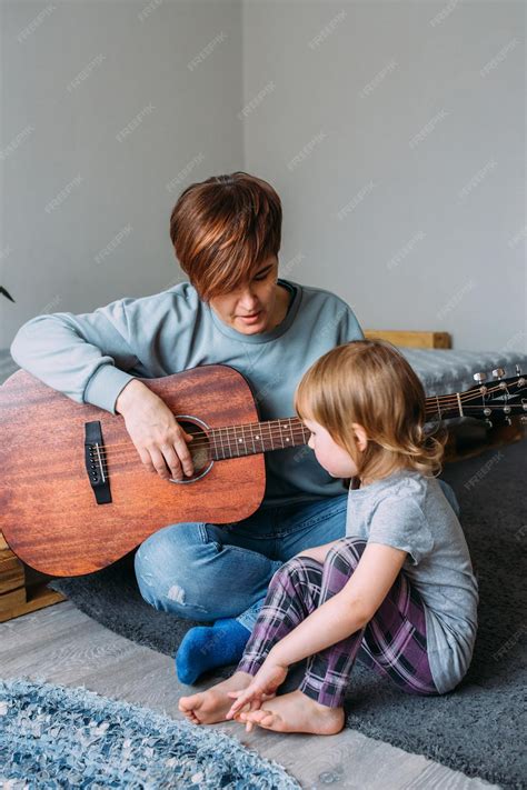 La Niña Toca La Guitarra Con Su Madre En El Suelo En Casa Foto Premium