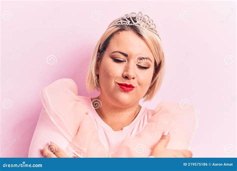 beautiful blonde plus size woman wearing pincess tiara with diamonds over pink background