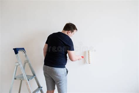 The Man Is Painting The Wall Diy Repair The Painter Holds The Roller