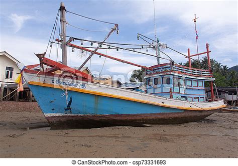Traditional Thai Fishing Boat And Wooden Houses At Low Tide Beach