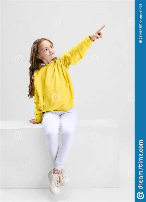 Full Length Portrait Of Beautiful Girl In Yellow Sweater Pointing