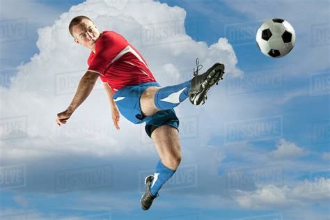 Soccer Player Jumping In Mid Air Kicking Ball Stock Photo Dissolve