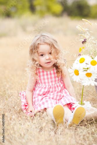 Cute Baby Girl 2 3 Year Old Sitting With Flowers Outdoors Looking At