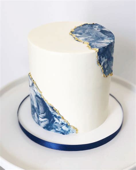 A White Cake With Blue And Gold Designs On It Sitting On A Plate Next To A Fork
