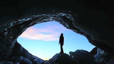 Male Figure In Glacier Ice Cave At Sunset