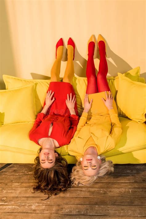 Retro Styled Beautiful Girls In Colorful Dresses Lying Upside Down On