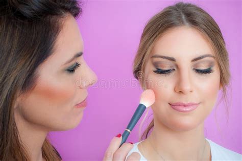 Makeup Artist Applying Makeup On Her Face Using Powder Brush Stock