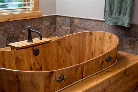 Soaking tub enclosure in dark wood with beige marble top sits beneath window and between matching vanities in this cozy bathroom. Brasada Ranch custom designed master bathroom with wood ...