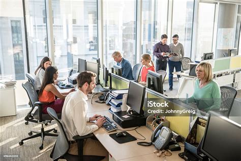 Office Workers At Desks Using Computers In Modern Office Stock Photo