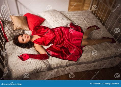 Sinnlicher Brunette In Einem Roten Kleid Das Auf Dem Bett Liegt