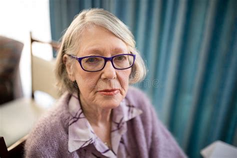 Portrait Of Senior Woman Sitting On Chair At Nursing Home Stock Photo