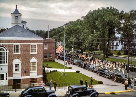 an old photo of cars parked in front of a building with people standing