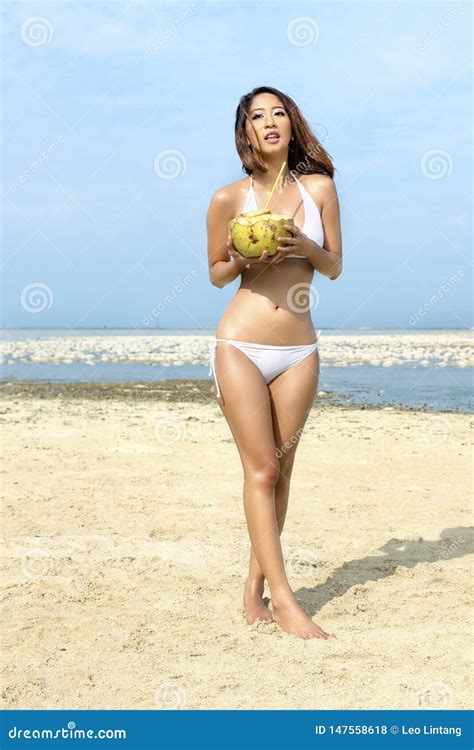 Menina Sexy Asi Tica No Biquini Que Guarda Cocos Na Praia Foto De