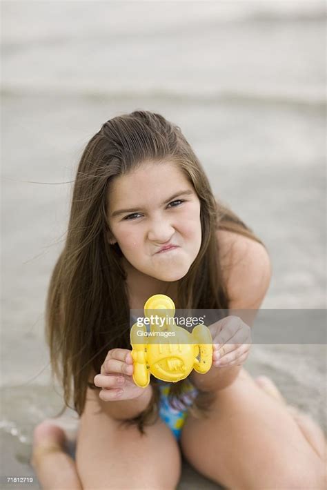Portrait Of A Girl Kneeling On The Beach And Holding A Toy High Res