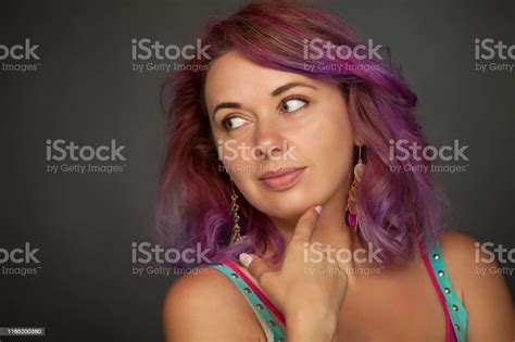 Studio Portrait Of A 30 Year Old Woman With Purple Hair On A Black