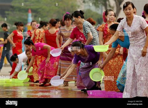 Chinese Women Of Dai Ethnic Minority Pour Water On The Ground To