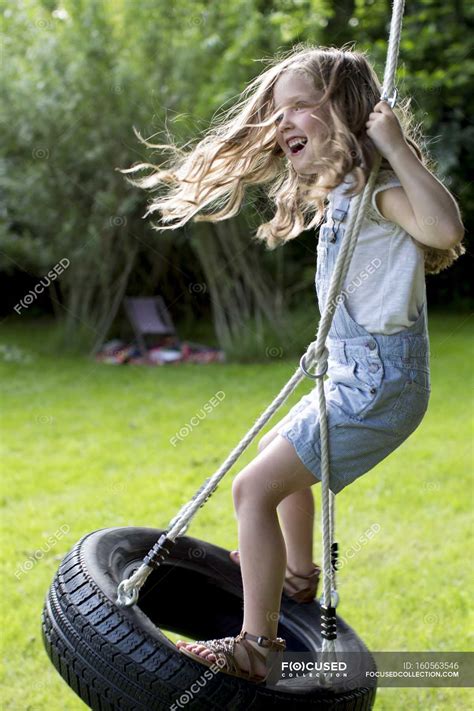 Girl Playing On Tire Swing In Garden — Action Motion Stock Photo