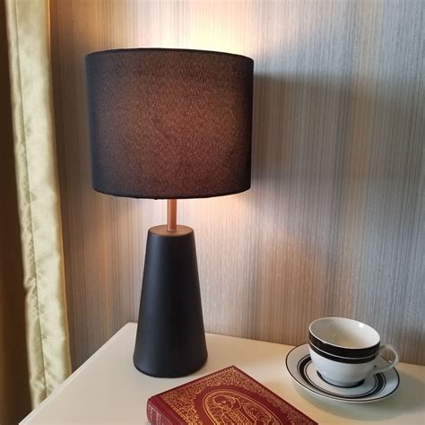 A Table With A Book Cup And Saucer On It Next To A Lamp