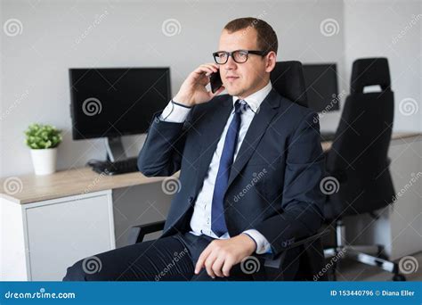 Portrait Of Handsome Businessman Talking By Phone In Office Stock Photo