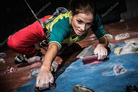 Young Woman Practicing Rock Climbing On A Rock Wall Indoors Stock Photo