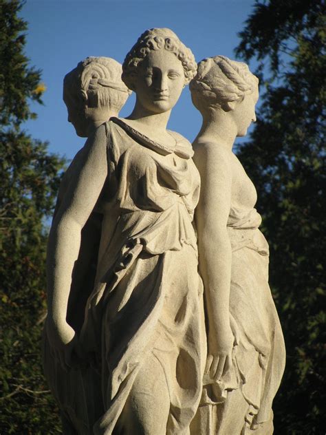 two statues standing next to each other in front of trees