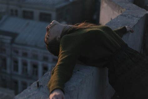 A Woman Laying Down On Top Of A Building