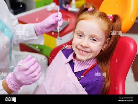 The Child Is A Little Red Haired Girl Smiling Sitting In A Dental Chair
