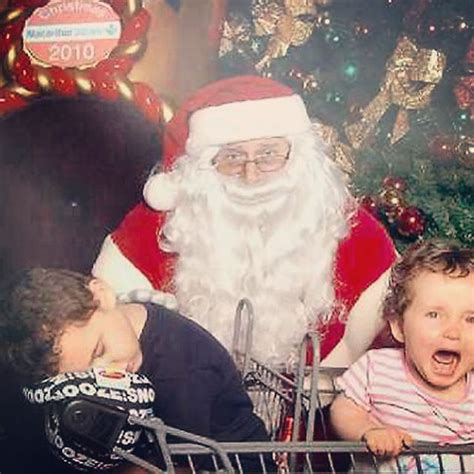 A Little Boy Sitting In Front Of Santa Clause With His Mouth Open And