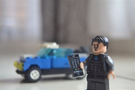 Lego Toy Action Figure Holding Remote Next To Blue Lego Vehicle Free Image Peakpx