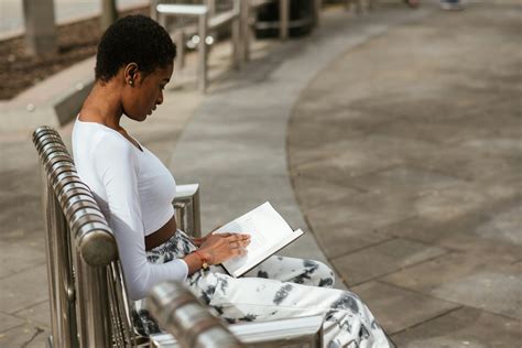 Focused Black Woman Reading Book On Street Bench · Free Stock Photo
