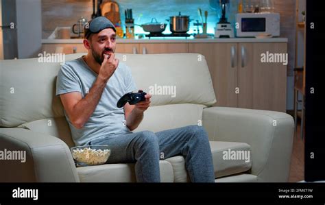Upset Pro Gamer Sitting On Couch And Playing Soccer Videogames For