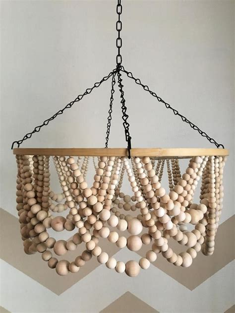 A Chandelier Made Out Of Wooden Beads Hanging From A Chain On A Wall