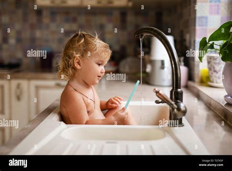 Baby Taking Bath In The Kitchen Sink Child Playing With Water And Soap